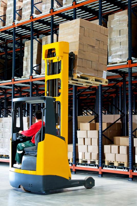 A man operates a forklift to place inventory in a warehouse.