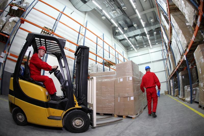 A forklift driver moves toward a pallet of boxes.