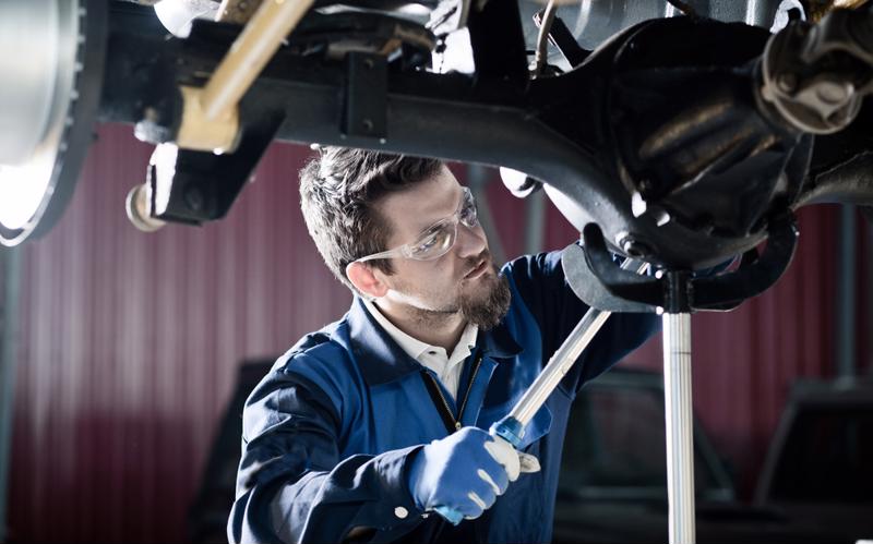 A man works on a raised vehicle.