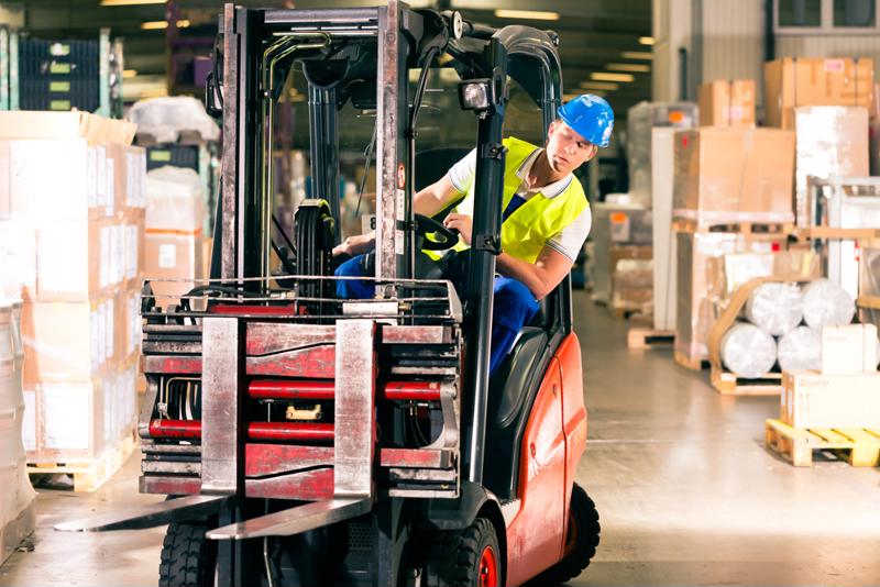 A man leans out of his forklift to look at the path ahead.