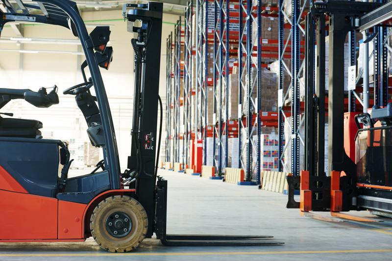 A forklift with lights stands in a warehouse aisle.